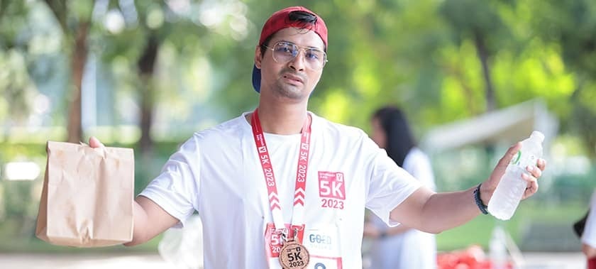 5k Run participant posing at the end of the race with their medal, water, and a gift bag.